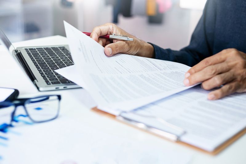 Foto: Person mit Dokumenten und Laptop