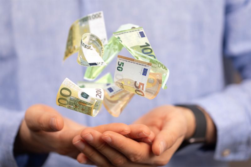 Foto: Hand mit schwebenden Geldscheinen